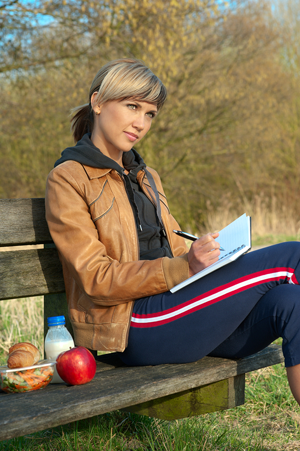 Woman writer on park bench writing